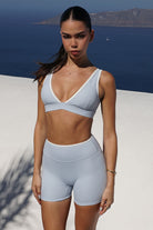Deep V Duo - טופ ספורט לנשים עם מחשוף V עמוק, עיצוב קונטרסט, קאפים נשלפים ובד מחטב וגמיש, מתאים לאימוני כושר, פילאטיס, יוגה וללבוש יומיומי.